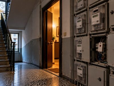 Un cortile di case popolari a Milano con panni stesi ai balconi e una mamma che accompagna un bambino