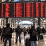 Pendolari davanti al tabellone delle partenze alla Stazione Centrale di Milano in un giorno di sciopero